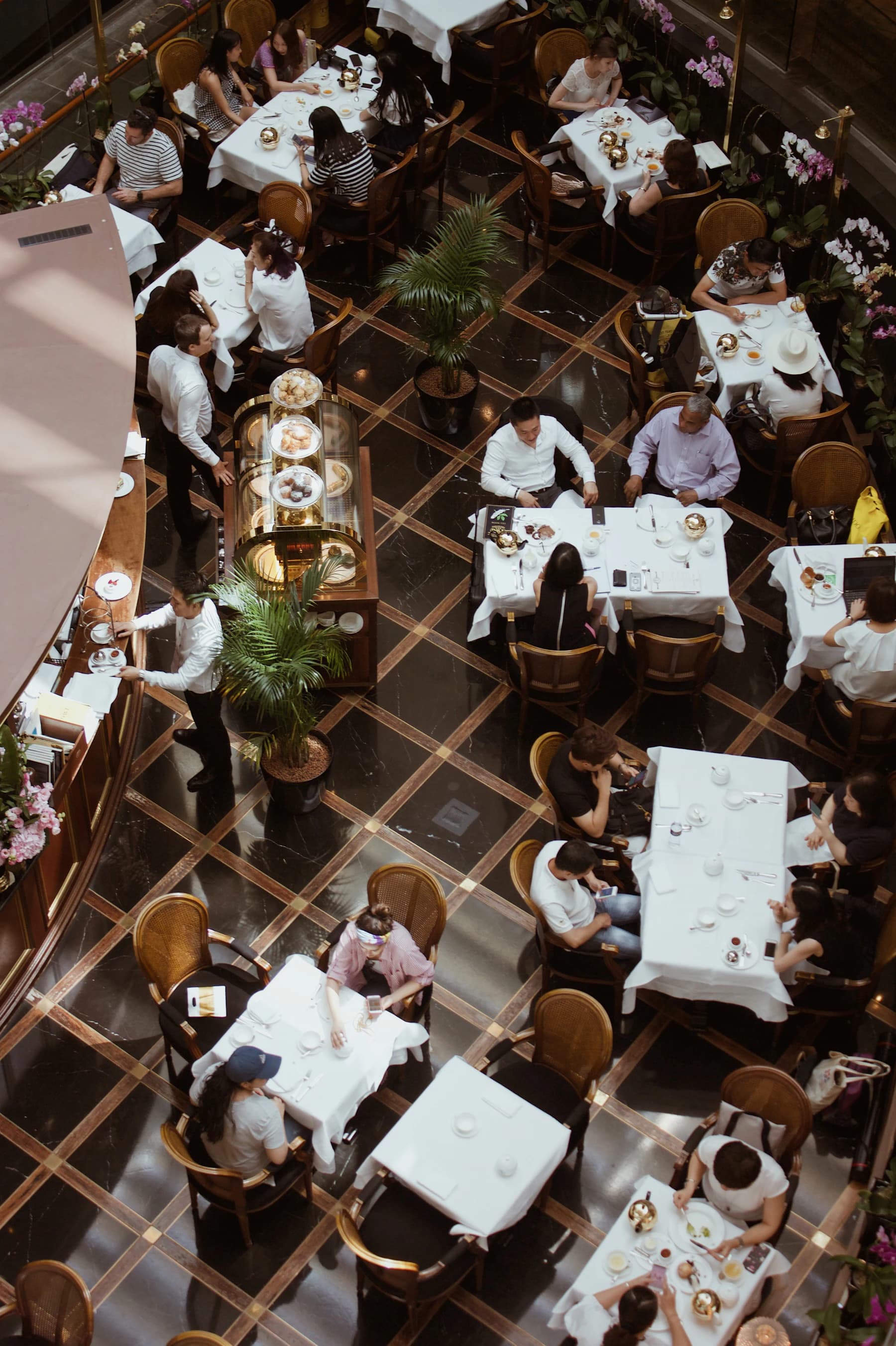The dining room seen from above: white tablecloths, brass lamps and diners mid-conversation.