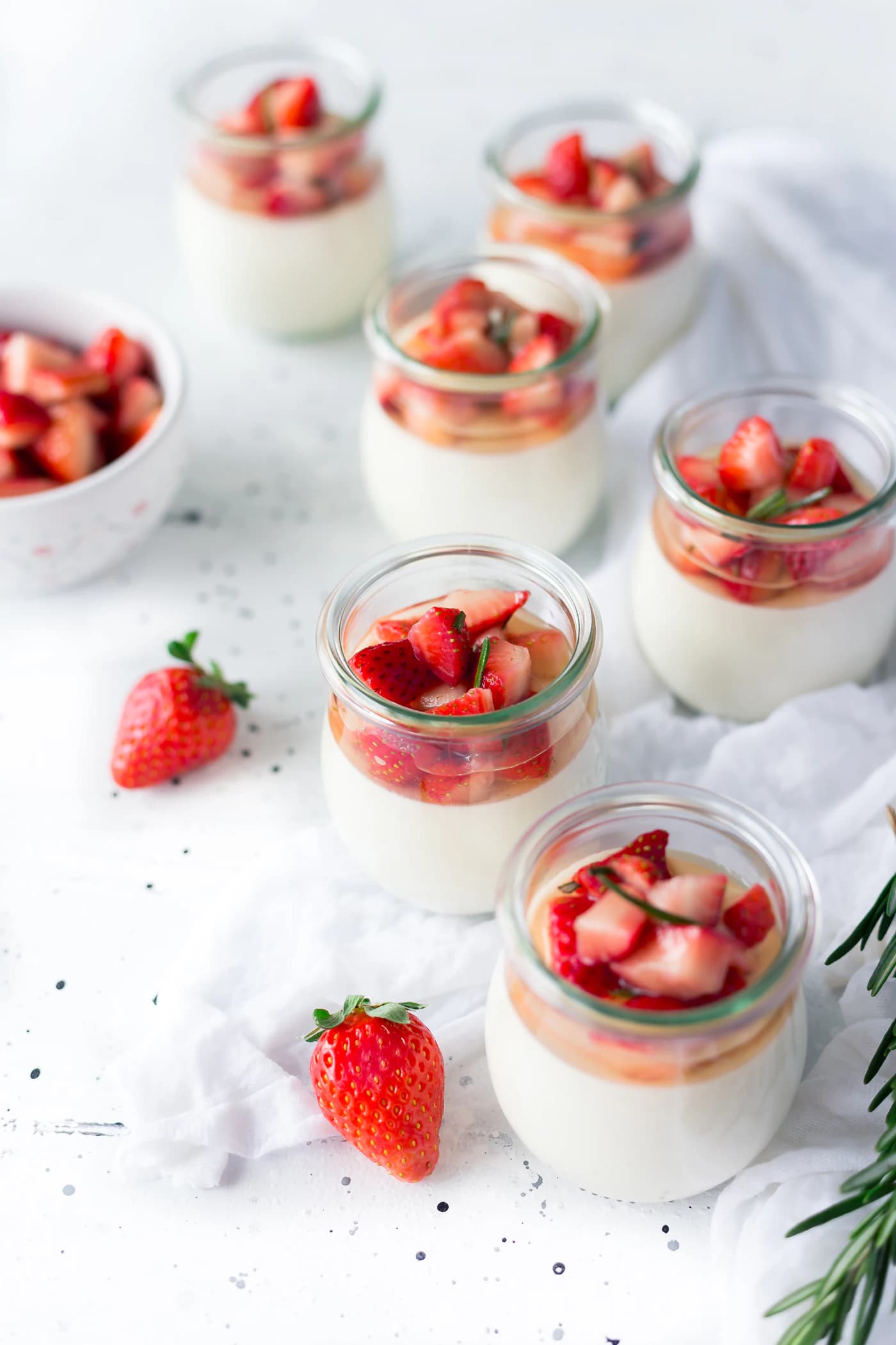 Panna cotta in small glass jars topped with chopped strawberries.