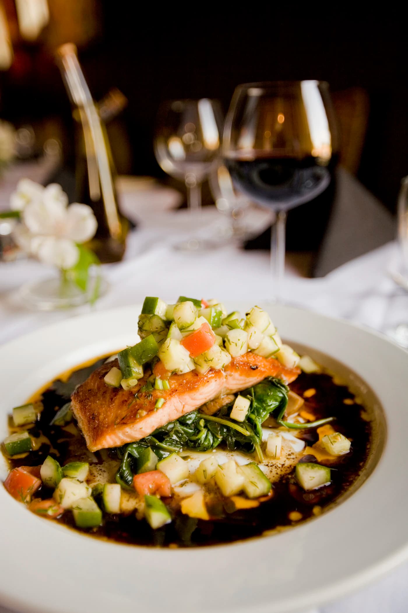 A seared fish fillet over greens in a dark broth.