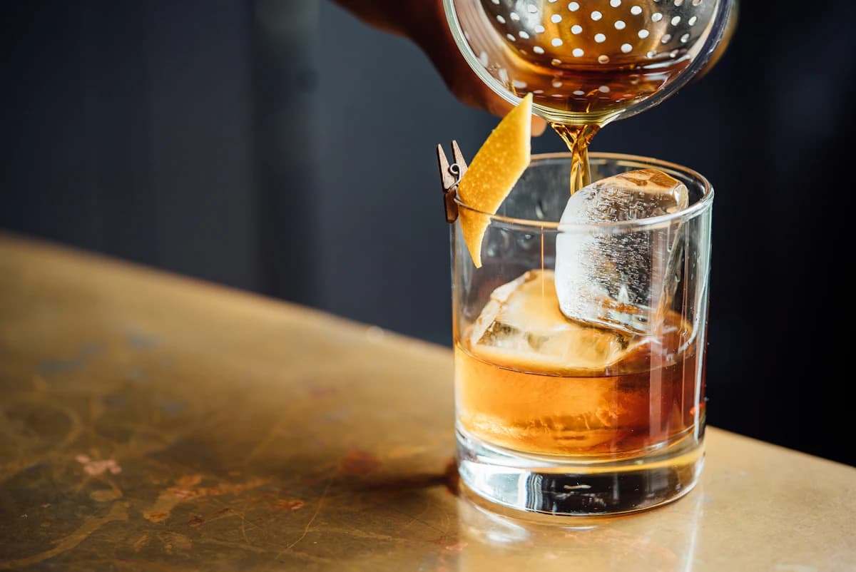 A whisky cocktail poured over a single large ice cube.